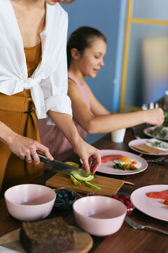 Woman is slicing an avocado while her daughter is cooking something else 