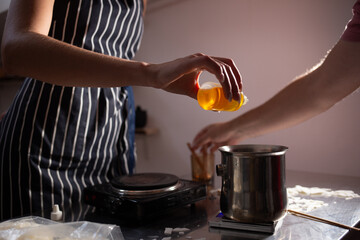 The woman adds flavoring agent to candle wax