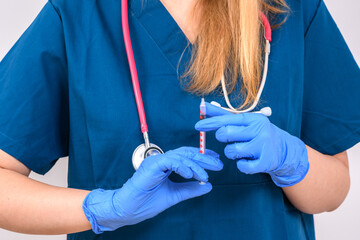 Pielęgniarka trzymająca w dłoniach strzykawkę z igłą  - obrazy, fototapety, plakaty