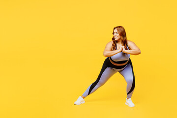 Fototapeta na wymiar Full body fun young chubby plus size big fat fit woman wear blue top warm up training do stretch exercises squats look aside isolated on plain yellow background studio home gym. Workout sport concept.