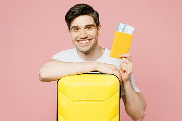 Traveler man wear summer casual clothes hold bag passport ticket isolated on plain pastel light pink background. Tourist travel abroad in free spare time rest getaway. Air flight trip journey concept.