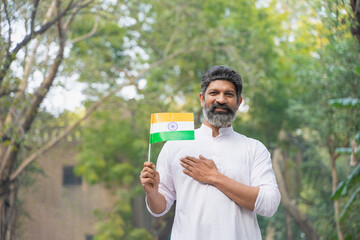 Indian man holding tri color flag in hand and celebrate nation festival.