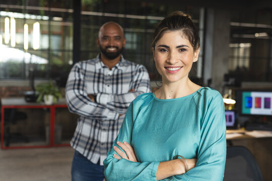 Portrait of happy diverse female and male colleagues with arms crossed smiling in office
