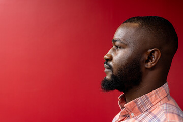 Side profile view of african american businessman against red background, copy space