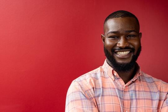 Portrait Of African American Businessman Smiiling Against Red Background, Copy Space