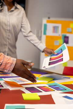 Mid section of diverse designers discussing over documents at modern office