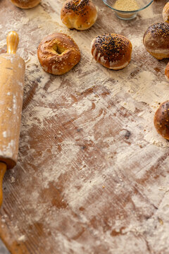 Close up of roller and fresh rolls with seeds on countertop with flour in bakery kitchen, copy space