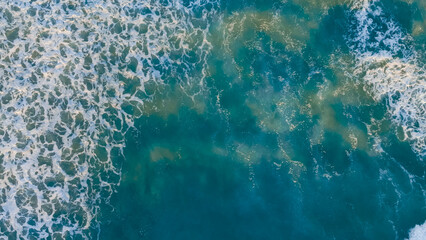 Waves crashing on a vibrant blue ocean with white foamy surf during bright daylight