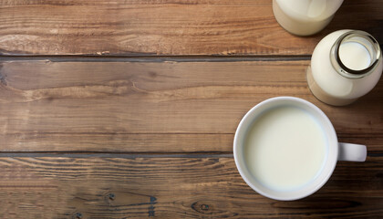 Milk cup and bottle on wooden table. Top view with copy space