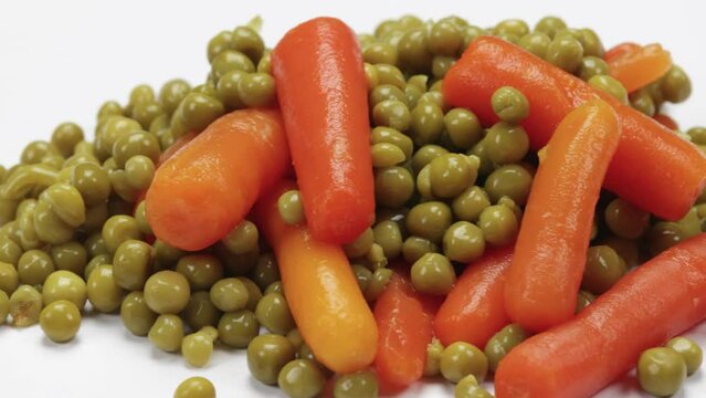 petits pois et carottes cuit, en gros plan, isol&eacute; sur un fond blanc