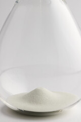 Close up of hourglass with white sand and copy space on white background
