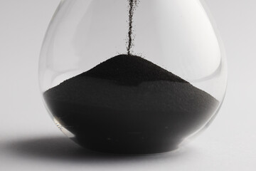 Close up of hourglass with black sand and copy space on white background