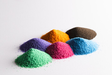 Close up of heaps of multi coloured sand and copy space on white background