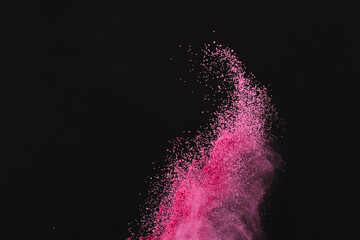 Close up of pink sand thrown in the air and copy space on black background