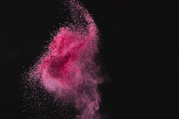 Close up of pink sand thrown in the air and copy space on black background