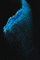 Close up of blue sand thrown in the air and copy space on black background