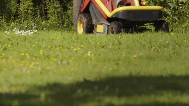 Professional lawn mower with worker cutting the grass in a garden
