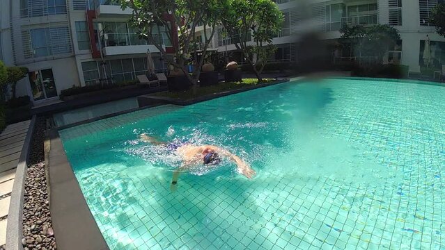 Man is swimming in the swimming pool on vacation. Slow motion video