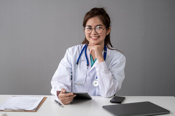 Smiling happy female doctor working with her laptop document  pills in the room hospital office, Young Asian lady doctor in white medical uniform with laptop working