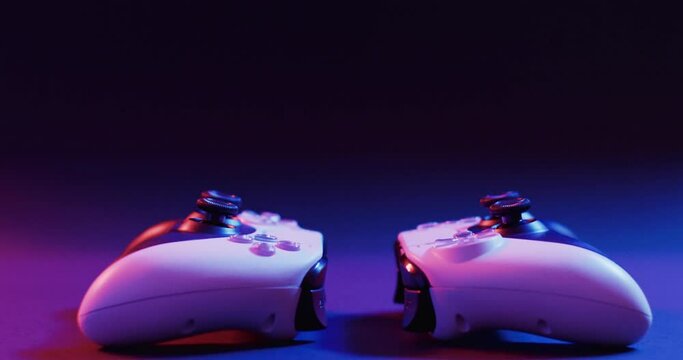Video of close up of video game pad controllers with copy space on neon background