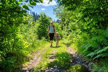 Obraz premium Mother with baby girl walking through green forest