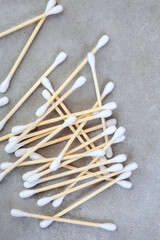 Natural wood and cotton ear buds on mottled gray background