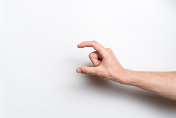 Close-up of a man's hand holding with his fingers an invisible object or item for a copy space with an advertisement on a white background.