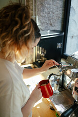 Young barista steaming milk