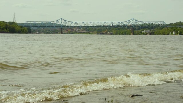 a view of Monaca East Rochester Bridge  in Western Pennsylvania with the waves of the Ohio river crashing on the rocky shore in the foreground