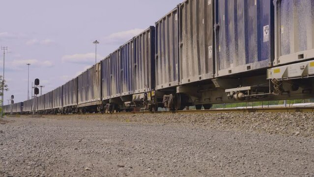 ground level view of a long train of blue box cars rolling slowly along the train tracks in the rust belt of Ohio known as Youngstown