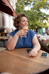Fototapeta premium Beautiful young woman sit in cafe with glass of cooly drink. Plus size woman drink red juice and smiling