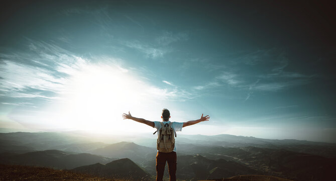Happy man with arms up standing on the top of the mountain - Successful hiker celebrating success on the cliff - Life style concept with young male climbing in the forest pathway