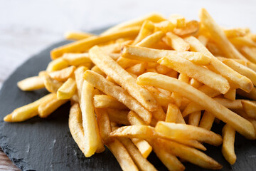 Fried potatoes, french fries on wooden table. Close up