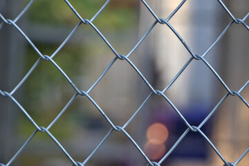 Close-up photo of wire mesh fence There is background blur and bokeh.