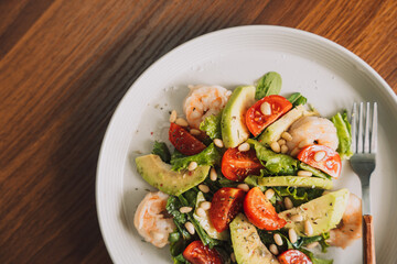 Vegetable salad with nuts on a white plate with a cup of coffee.