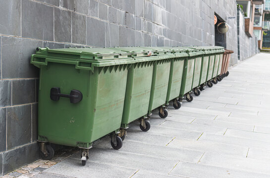 Recycling bins in a row in front of a wall