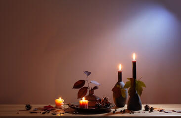 autumn dark decor with candles on wooden shelf on background wall
