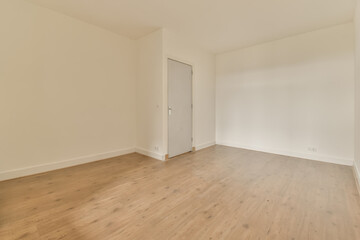 an empty room with wood floors and white walls, there is a door leading to the left side of the room