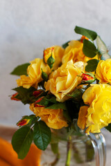 Beautiful bouquet of fresh yellow garden roses in a glass vase on a light background close up. Selective focus
