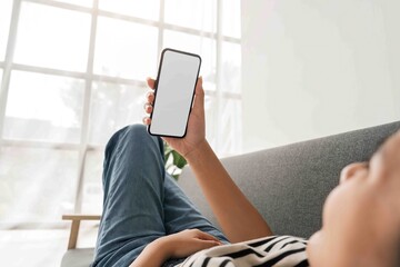 Young woman asian relaxing on comfortable sofa and holding mobile phone with white screen