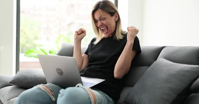 Excited woman looking at laptop screen screaming with joy. Girl surprised by message with good news