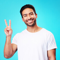 Portrait, man and peace fingers in studio for hope, self love and show icon on blue background....