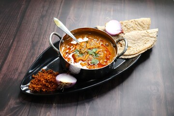 Traditional Sev bhaji or sev tamatar nu Shaak with Jowar Bhakri. Sev is a crisp fried gram flour vermicelli. Served with chopped onion and lemon. with Copy space. Its a sweet and spicy indian curry.