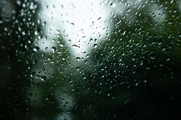 Rain water droplets accumulating on a car's window glass. Close up shot, shallow depth of field, no...