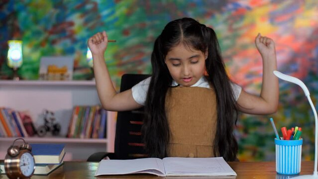Portrait of a young school-going girl making notes - studious child  lazy  sleepy during studies  late night study  girl child. A tired girl yawning / feeling sleepy while studying at home - boring...