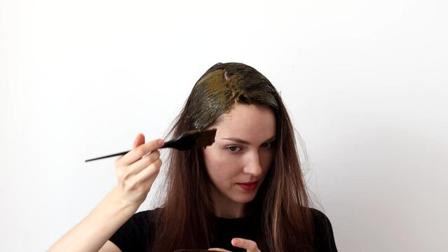A young woman dyes her hair with an herbal mixture of henna and basma to produce a brown color