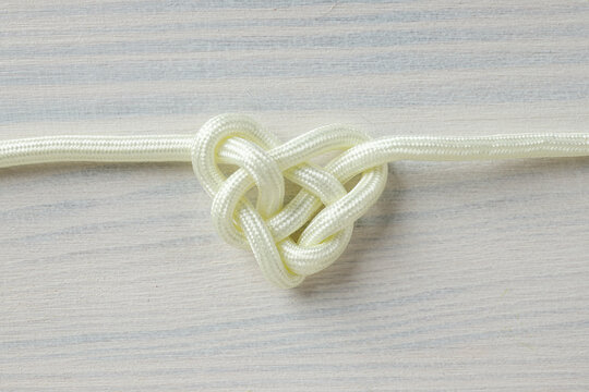 Celtic knot in the shape of a heart made of white cord. Concept of creative unity, faith and protection.