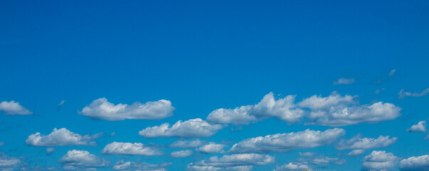 Fototapeta na wymiar Small puffy white clouds in a blue sky background