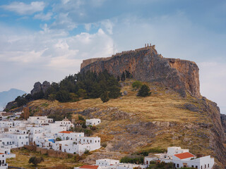 Fototapeta premium Lindos town in Greece aerial view in cloud summer day, white houses in Rhodes island , cityscape viewpoint traditional greek architecture, famous landmark and touristic destination concept