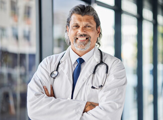 Portrait, man and doctor with arms crossed, smile and surgeon with confidence, career and medicine. Face, mature person and medical professional in a hospital, healthcare expert and happy employee